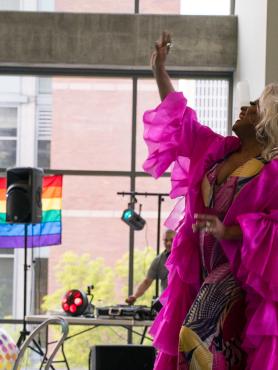 drag queen, Poison Waters, dancing in a glamorous pink silk robe over a yellow gown