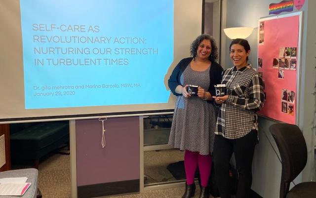 two queer people of color stand in front of a screen that reads :self care as revolutionary action"