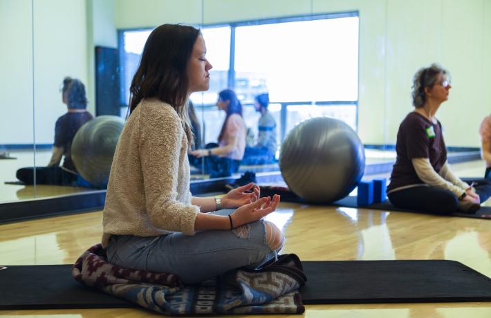 Women meditating on yoga mat during a fitness class.