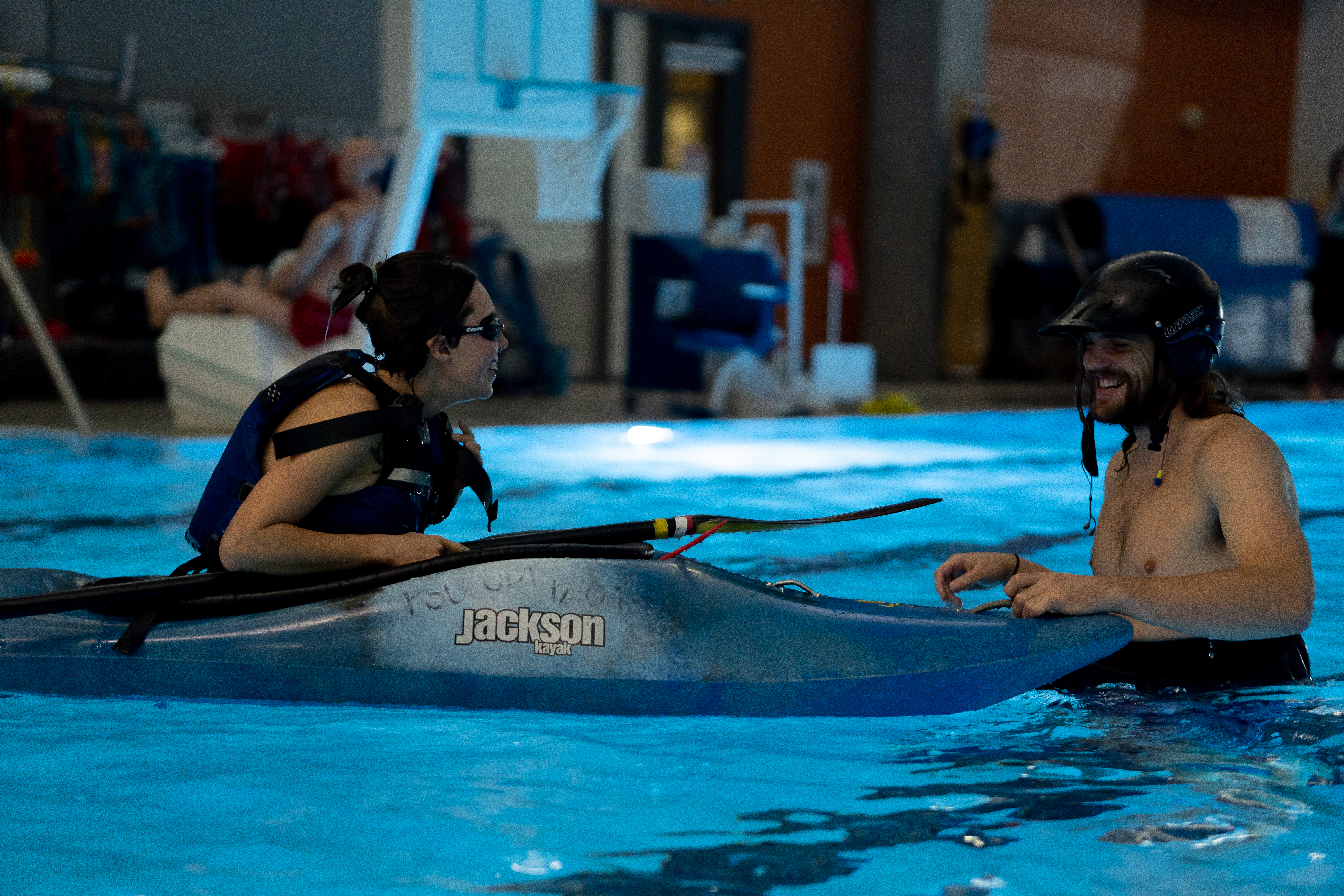 Two paddlers smile while kayaking in the pool