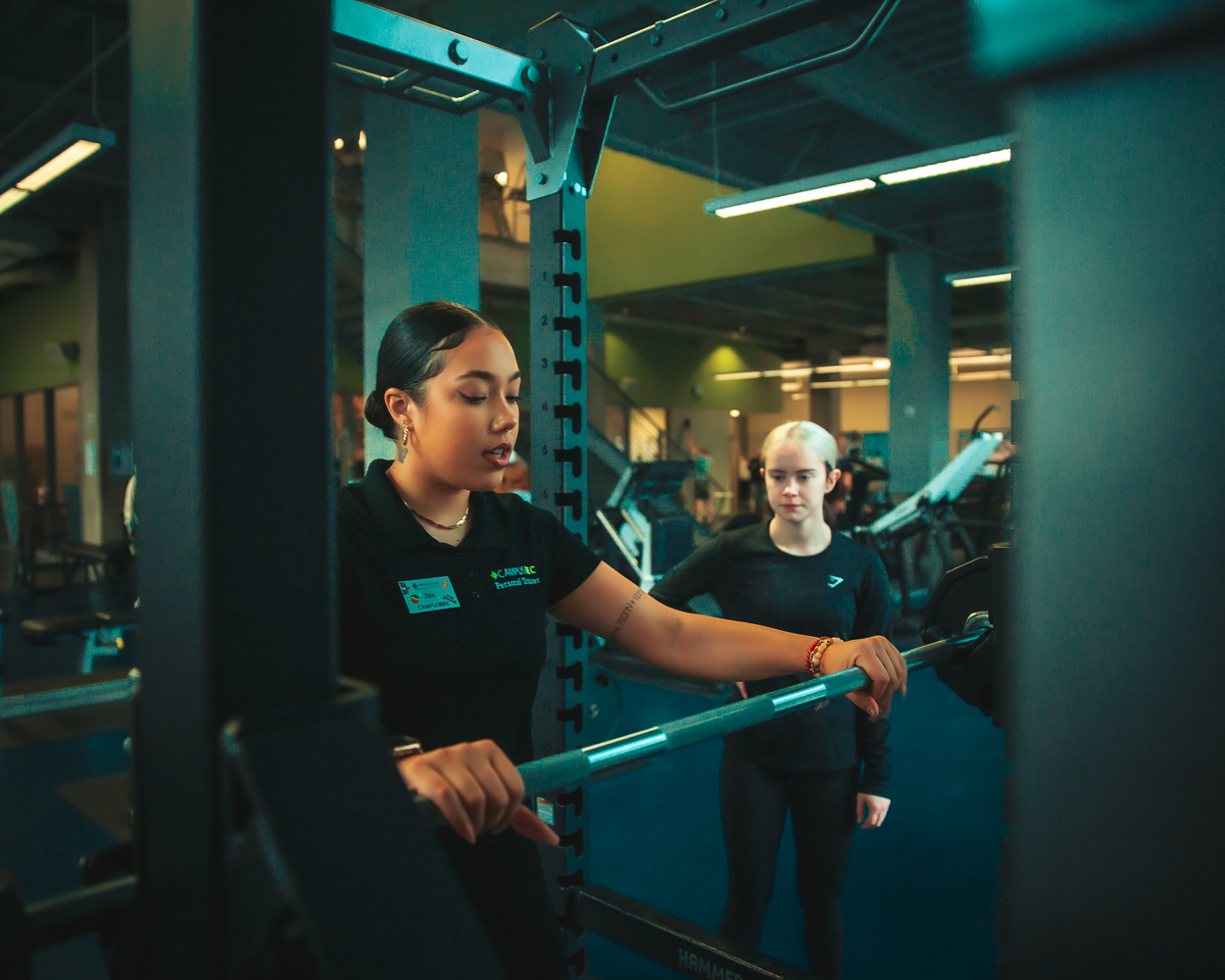 A Personal Trainer showing someone how to use a barbell