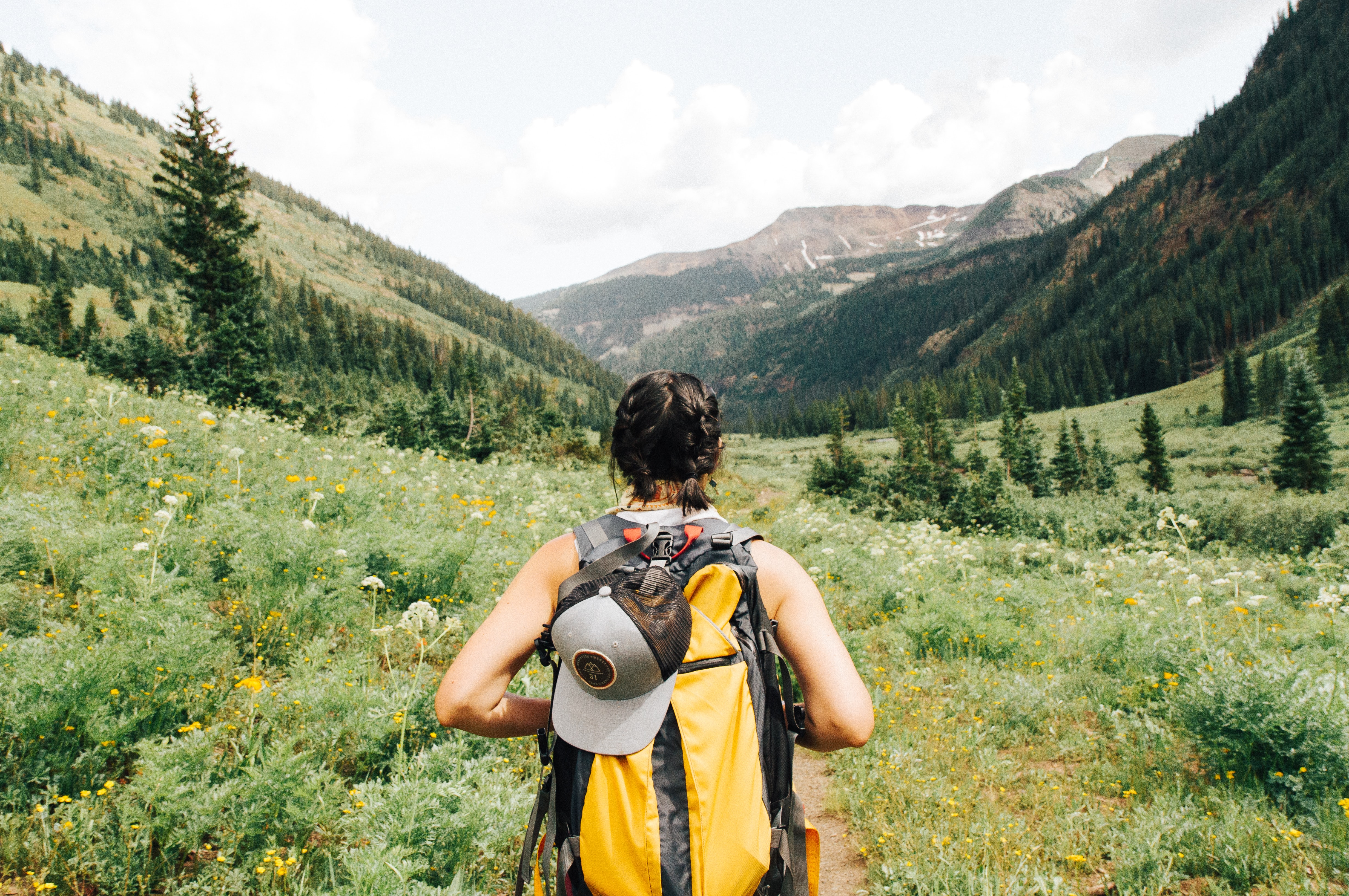 A person wearing a day pack hikes into a beautiful mountain landscape.