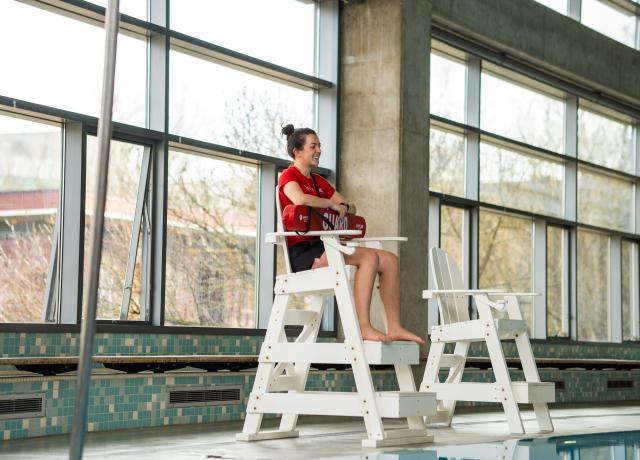 Person sitting on lifeguard chair overlooking pool