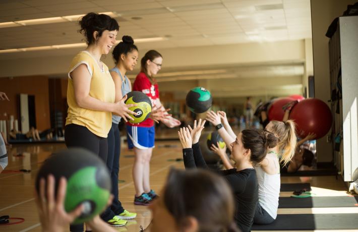 Group of people participating in ab exercises by throwing a weight ball back and forth.