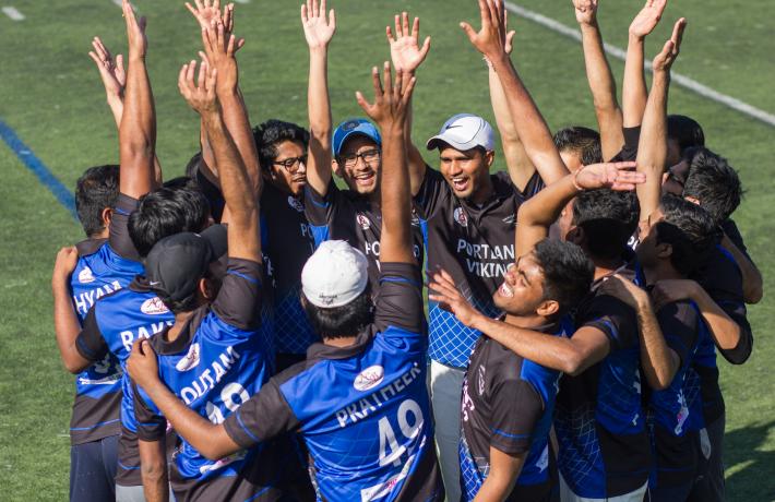 Cricket players celebrate in a team huddle.