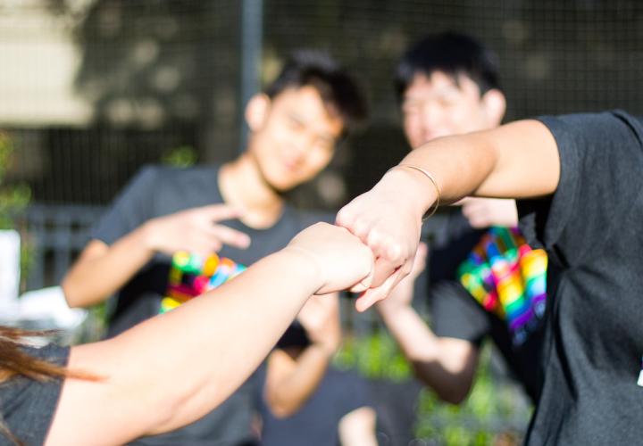 Two people wearing PRIDE t-shirts fist bump at the 2019 Pride softball tournament.