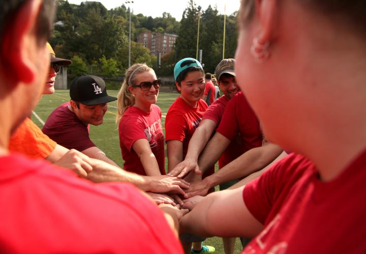 Softball teammates putting their hands together before play.