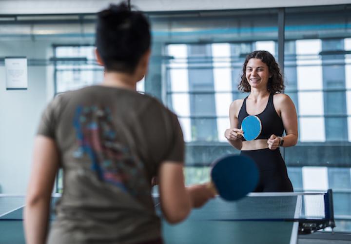 Two people smile while playing table tennis
