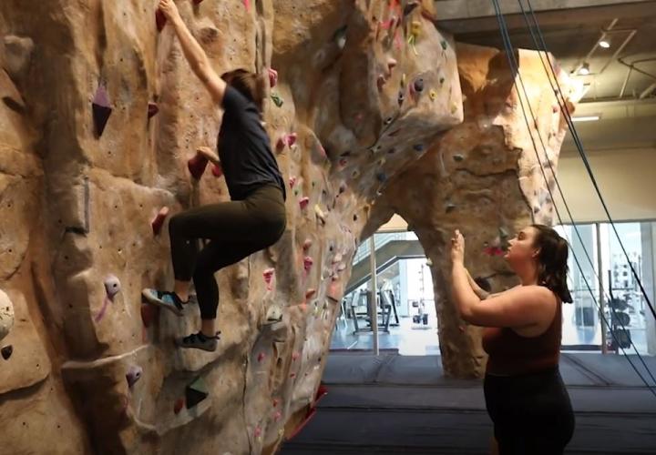 Person helping someone learn to climb