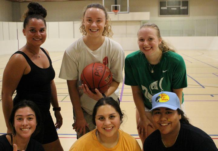 women posing with a basketball