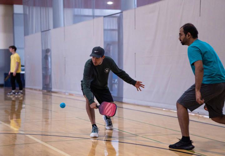 A person reach to hit a pickleball. 