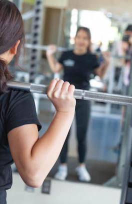 Personal Trainer standing in front of mirror doing squats with weights.