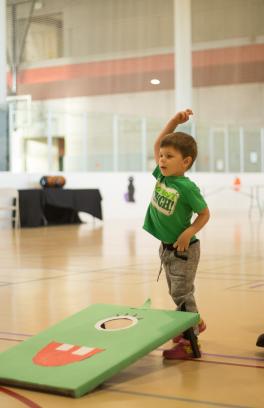 Little boy tossing bean bag into hole.