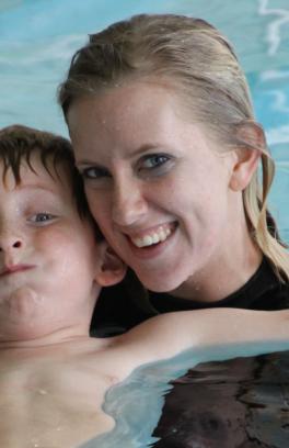 A woman smiles while swimming with a youth member in the Rec Center pool