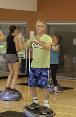 People stand on bosu balls in a Group X class