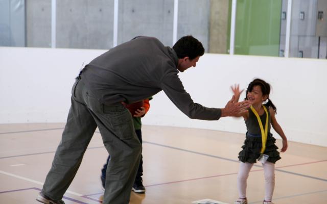 A youth member smiles and gives an adult a high five on the Rec Center courts