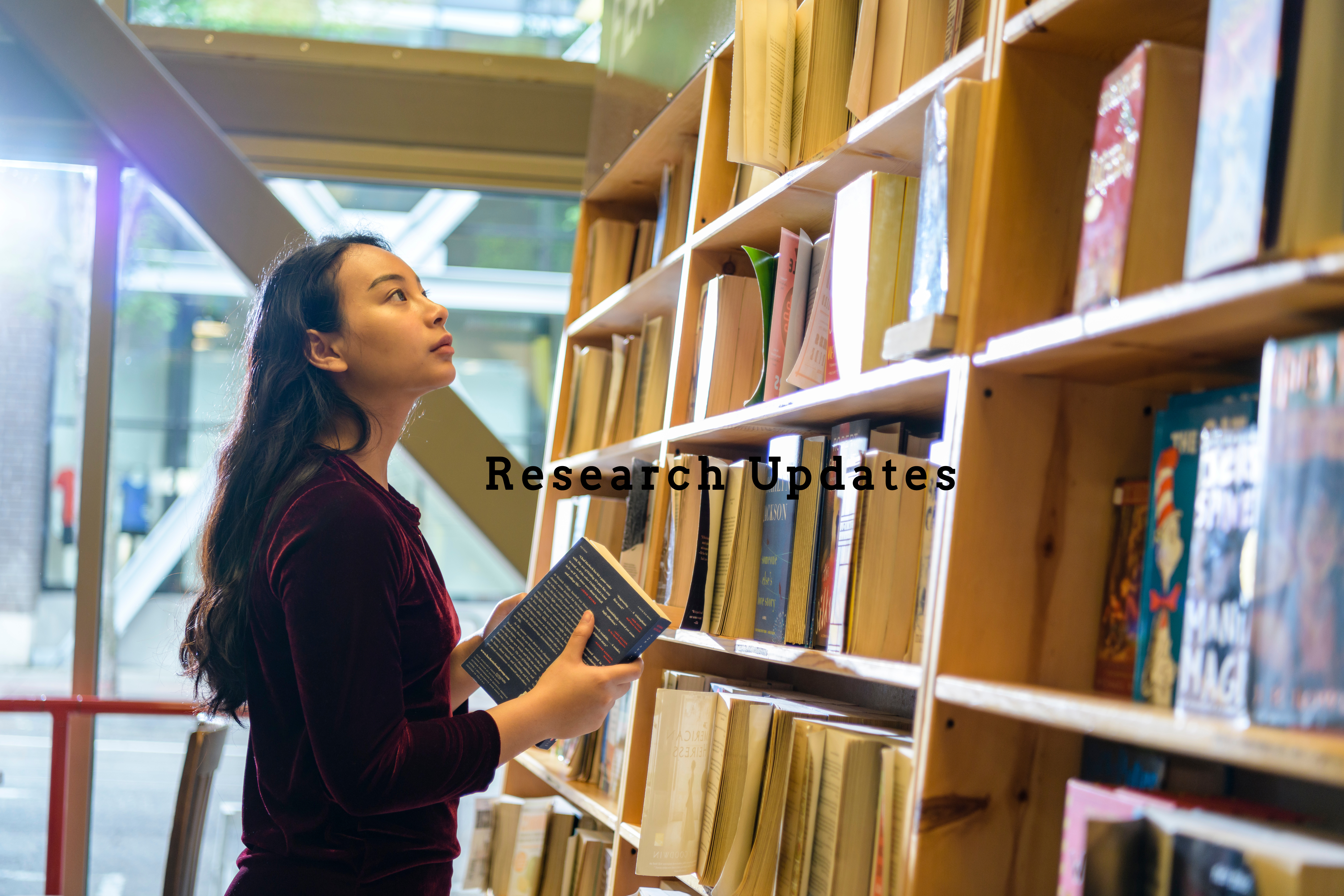 Woman looking at bookcase with words Research Updates