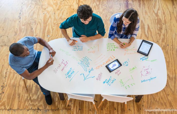 People working on a dry erase conference table.