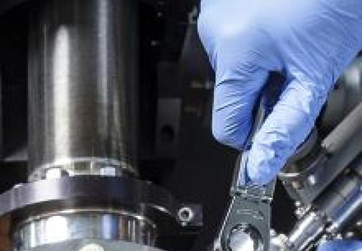 An image of a lab technician tightening a bolt on a piece of equipment