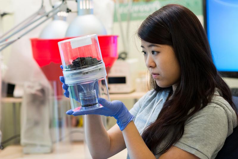 Student wearing gloves holds a plastic chamber.