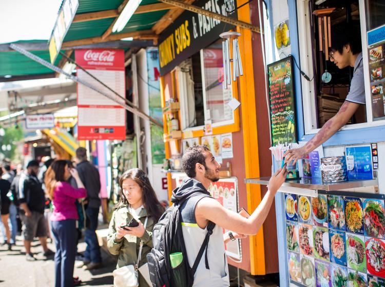 Student paying for lunch at a food cart downtown