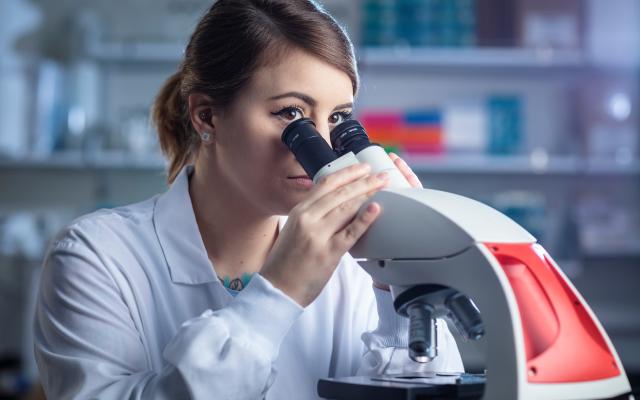 woman looking into microscope