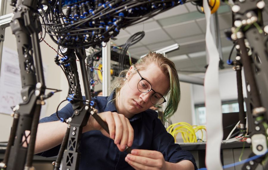 PSU student working on a complex robotic structure in an engineering lab