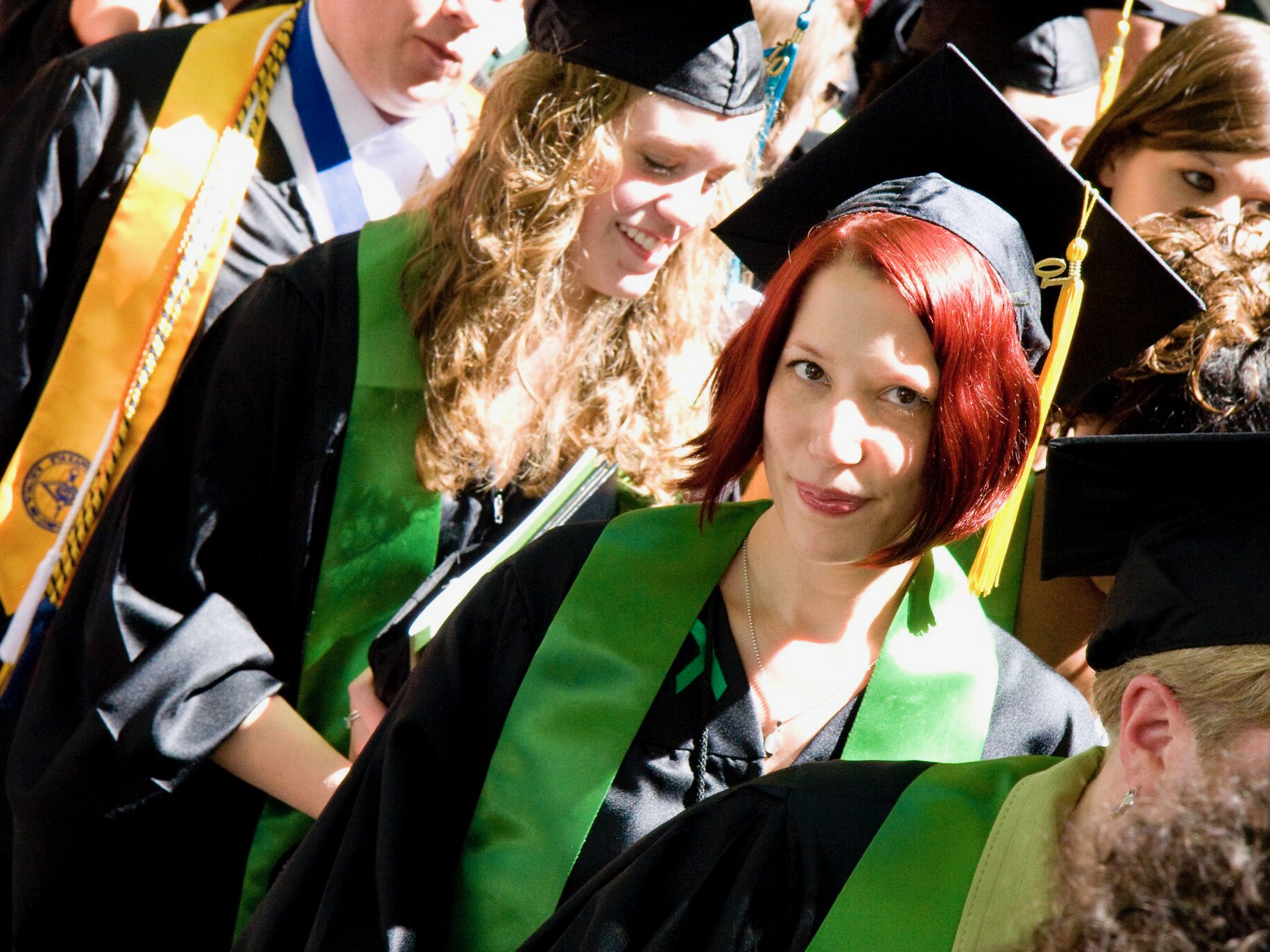 There are two people wearing graduation regalia. 