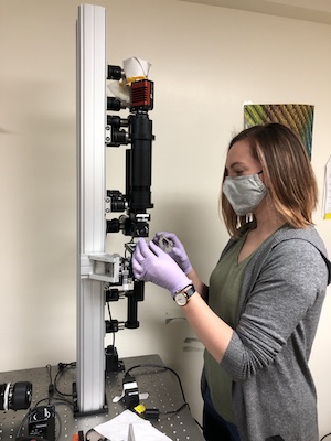 student with mask and gloves using a microscope 