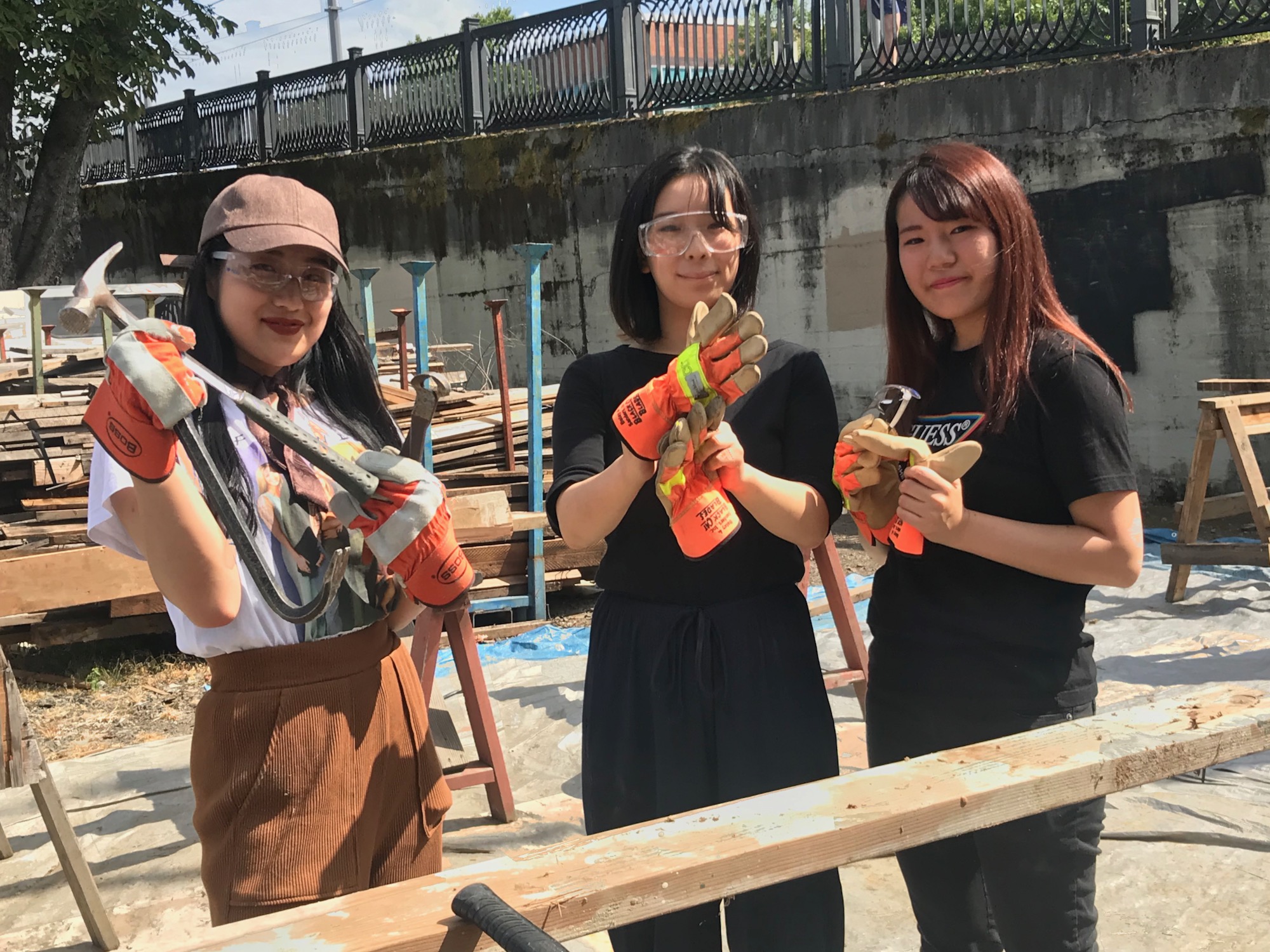 The image is of three people holding tools and construction gear. 