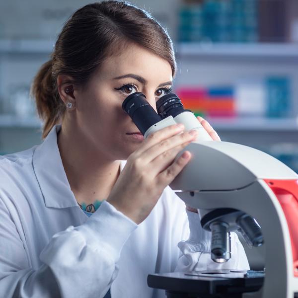 woman looking into microscope