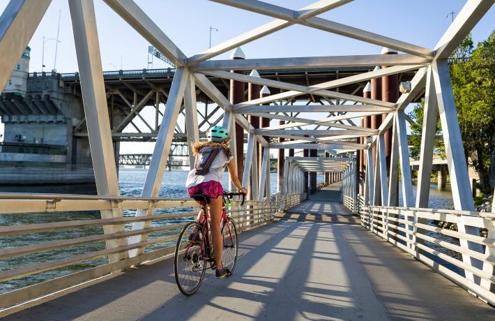 A PSU student riding a bike through a bridge bike path next to the river.