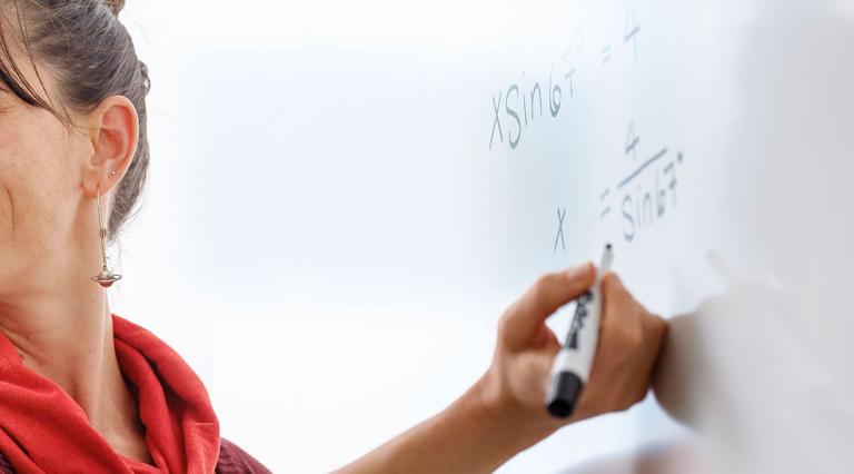 Instructor doing math on a white board