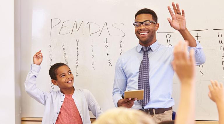 Teacher in a classroom raising hand