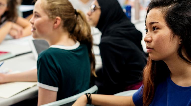 A group of high school students in class look off to the left.