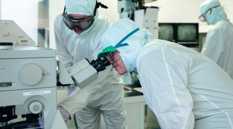 two physics grad students in white lab coats in a semiconductor lab