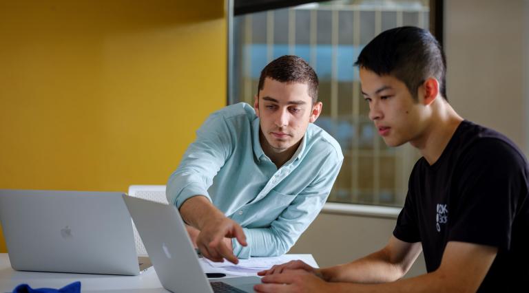 student on laptop with instructor pointing to screen