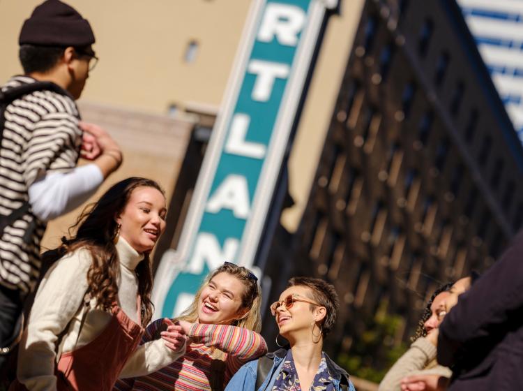 Students hanging out on Broadway in front of the Portland theater sign