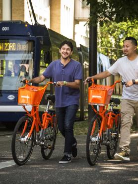 Students walking on campus with bikes.
