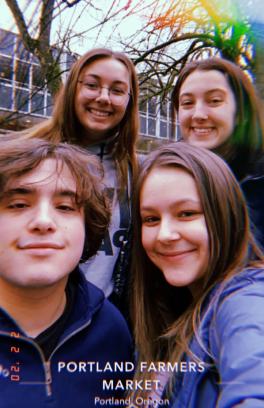 There are four people in the Park Blocks at Portland State smiling for the camera.