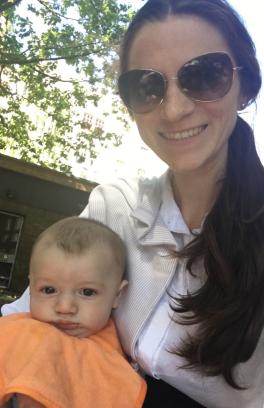 There is a person wearing sunglasses, they are holding a baby.