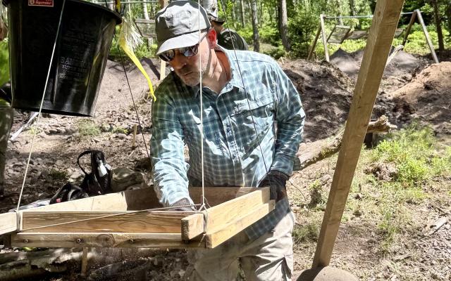 PSU anthropology professor Jeremy Spoon sifts soil at a World War II crash site in Germany