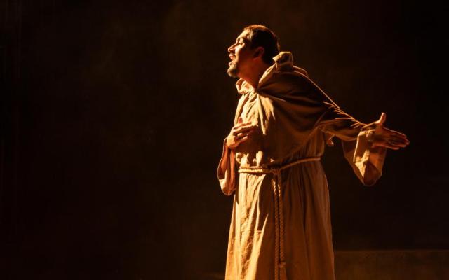 A performer in PSU’s 2024 production of Measure for Measure sings under dramatic stage lighting
