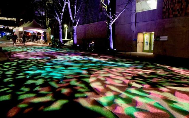 Colorful abstract light patterns projected onto a paved walkway on the PSU campus at night