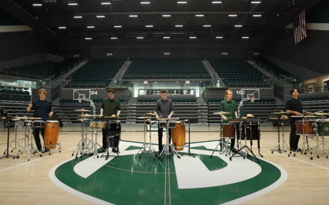 Five PSU Percussion Ensemble students perform on the Viking Pavilion basketball court surrounded by percussion instruments