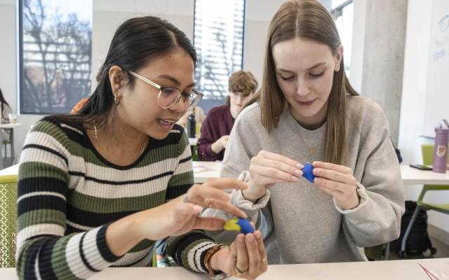 PSU students Joy Spettel and Brenna Robin shape colored clay into miniature brains in an elementary education class