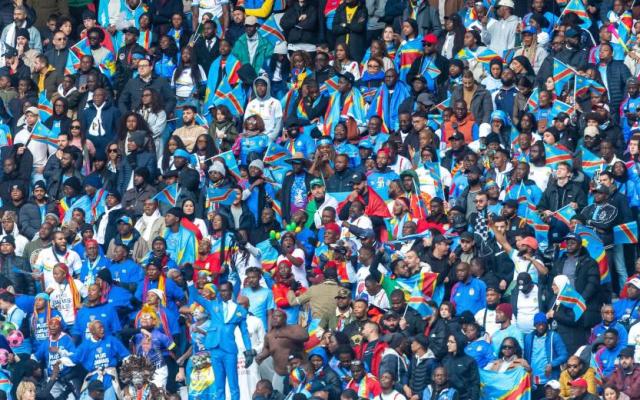 Fans of the Democratic Republic of Congo wave national flags in a packed stadium crowd