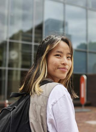 PSU student with backpack walks to class via the Urban Plaza