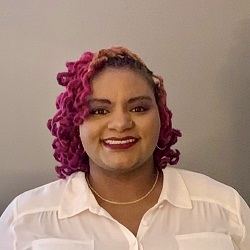 Smiling Black woman with pink hair and a white blouse