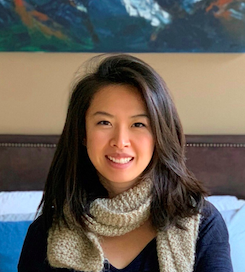 Image of Jane Zhu, a young asian woman wearing a scarf, smiling at the camera.